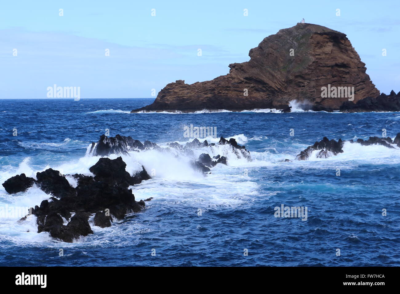 Raue Wellen spritzt über den schwarzen vulkanischen Felsen im Atlantik an der Küste Madeiras. Stockfoto