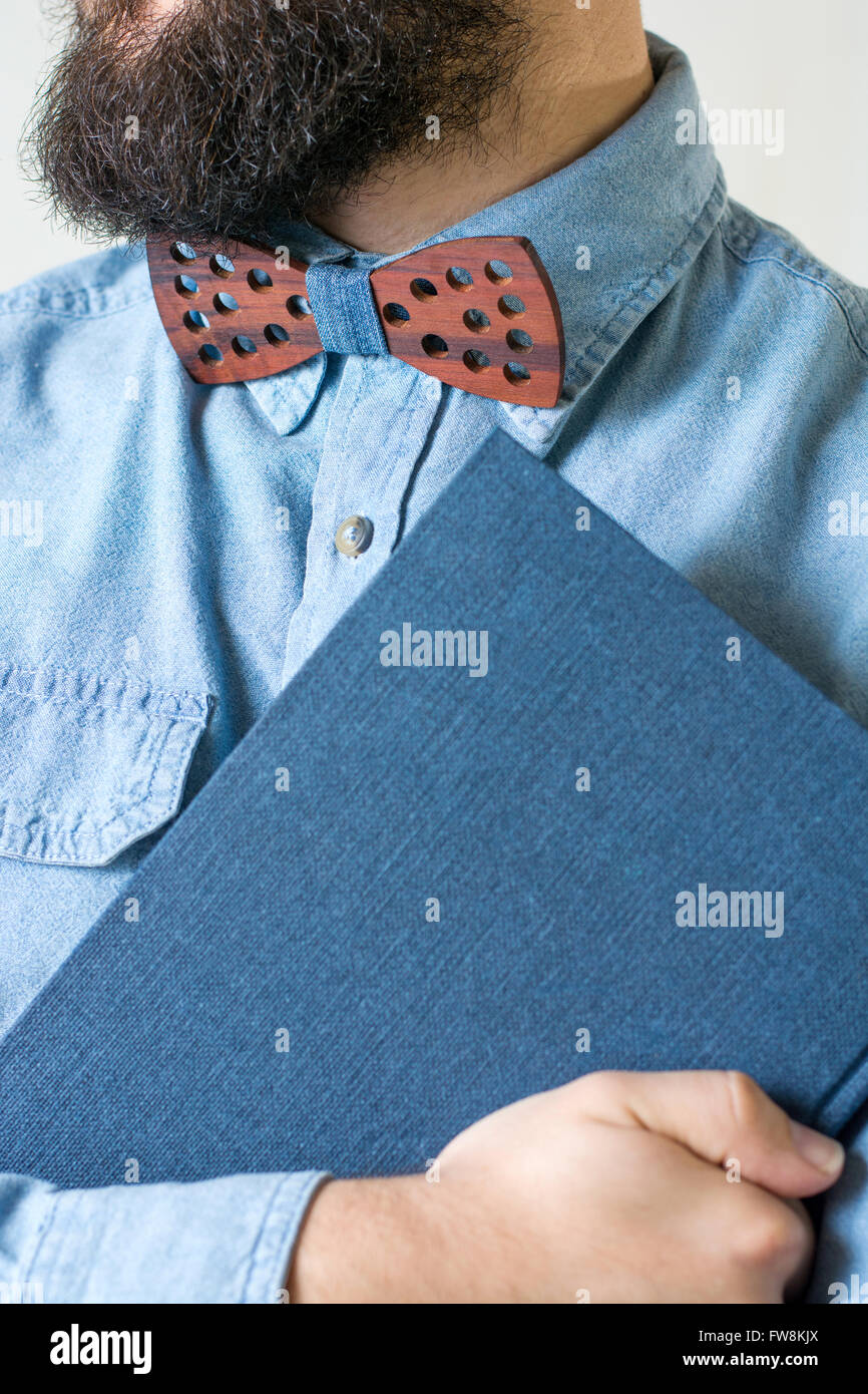 Bärtiger Mann mit einer hölzernen Fliege hält ein blaues Notizbuch Stockfoto