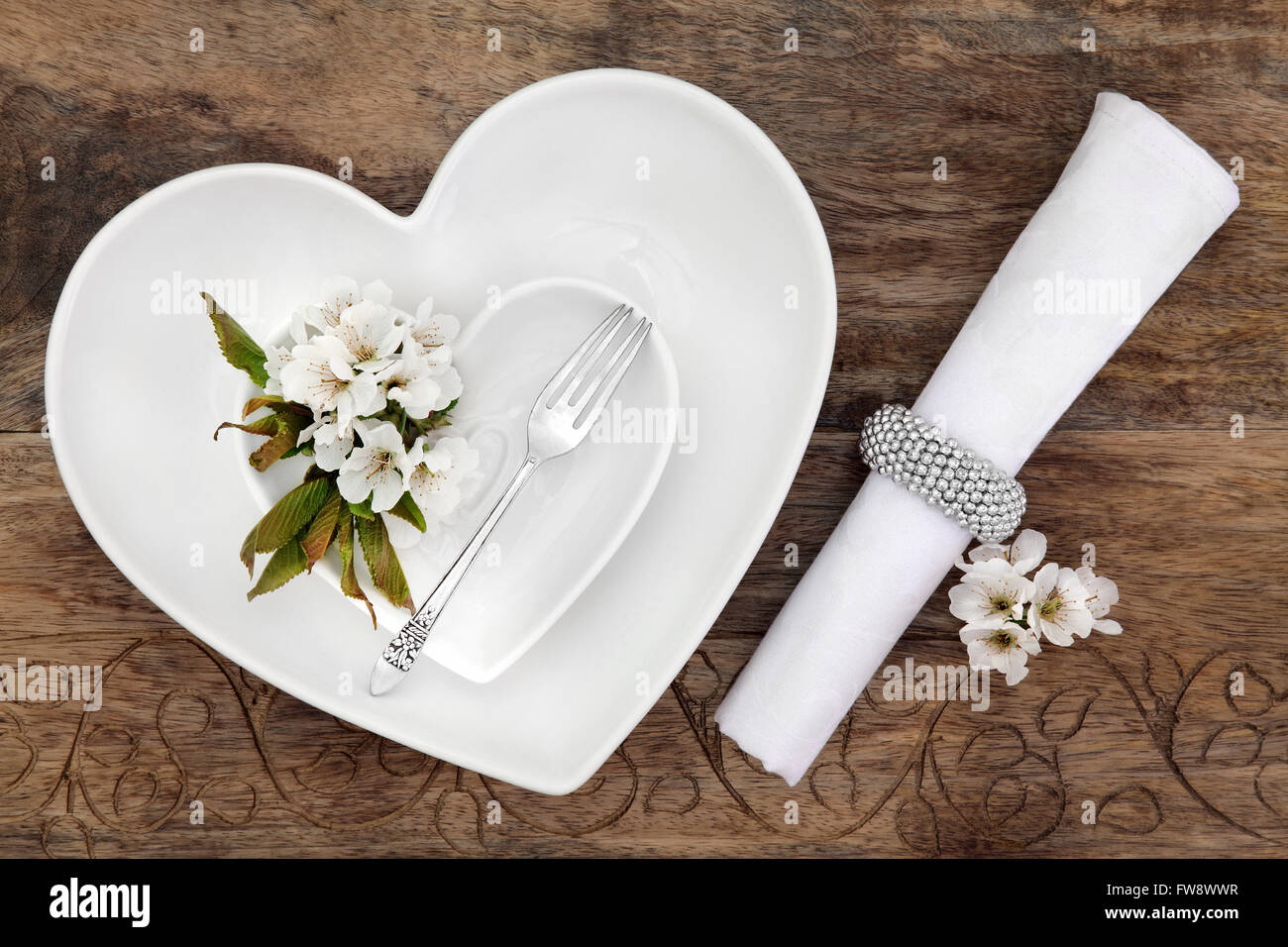 Romantischer Tischgedeck mit weißen Herzen geformt Porzellanschalen, Antik Silber Gabel mit Blume Blüte und Serviette. Stockfoto