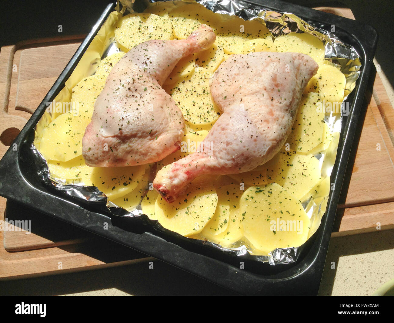 Roh marinierte Hähnchenschenkel mit Kartoffeln auf ein Backblech legen und  Schneidebrett Stockfotografie - Alamy