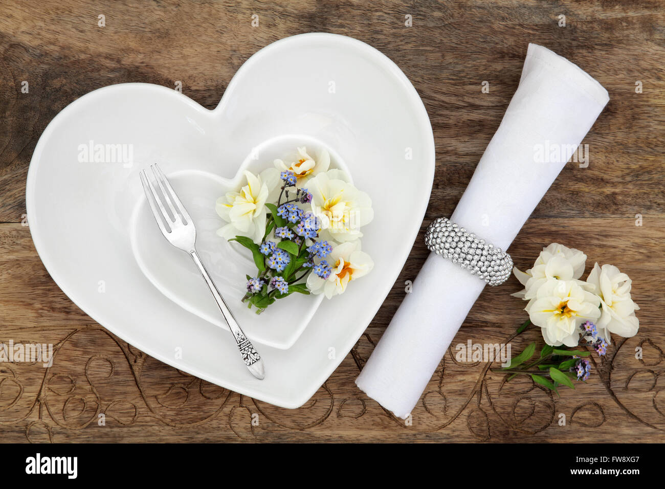 Tabelle-Gedeck mit weißen Herzen geformt, Porzellanschalen, Antik Silber Gabel, Feder Blume Auswahl und Serviette mit ring Stockfoto