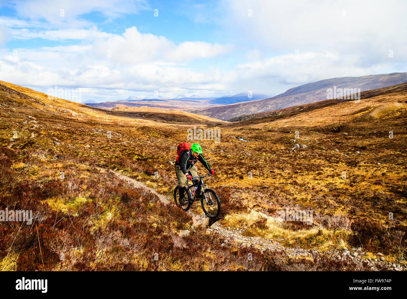 Mountainbiker auf Moorland über Glen Coulin in Torridon Highland Schottland mit den Gipfeln des Fannichs in der Ferne Stockfoto