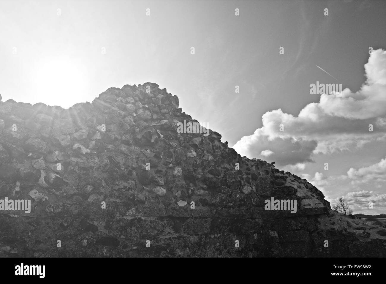 Ruinen einer Steinmauer gegen die Sonne mit einigen flauschigen Wolken und den Spuren der ein Flugzeug in den Himmel. Abtei St. Bennet Stockfoto