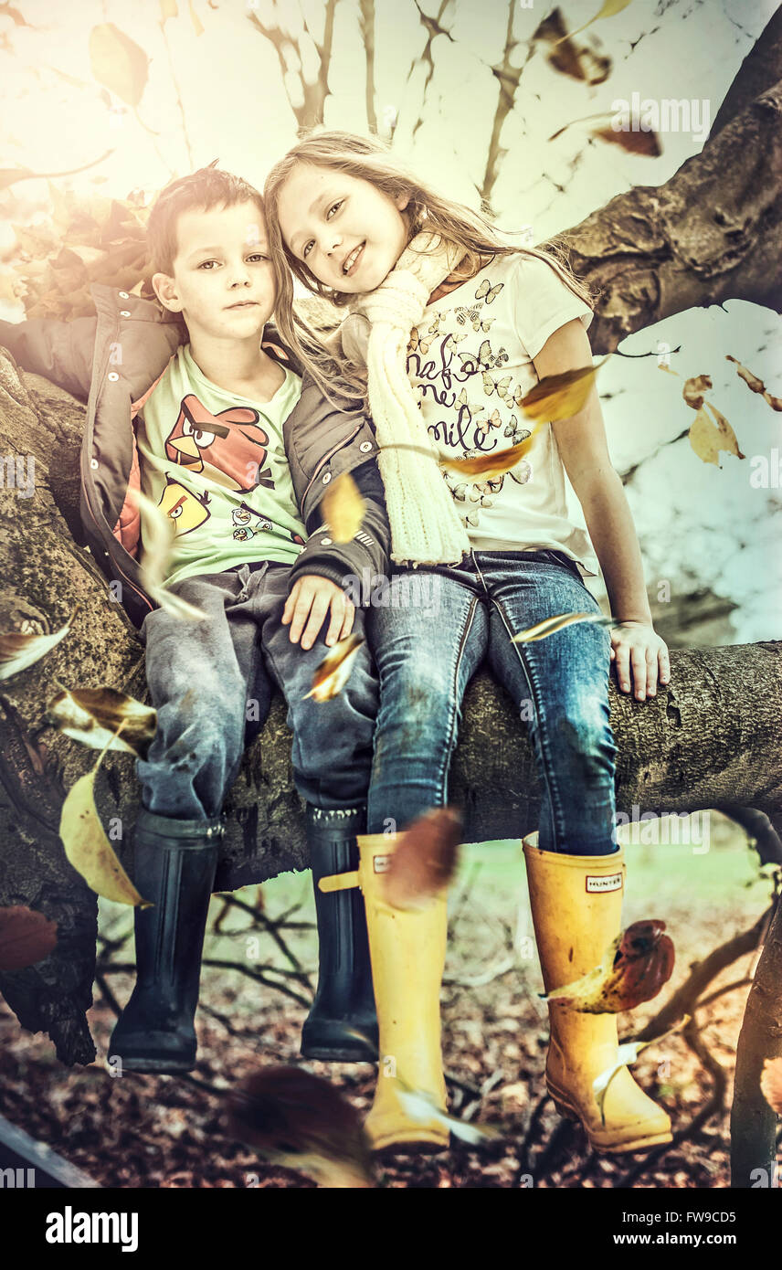 Bruder und Schwester sitzen auf Baum Stockfoto