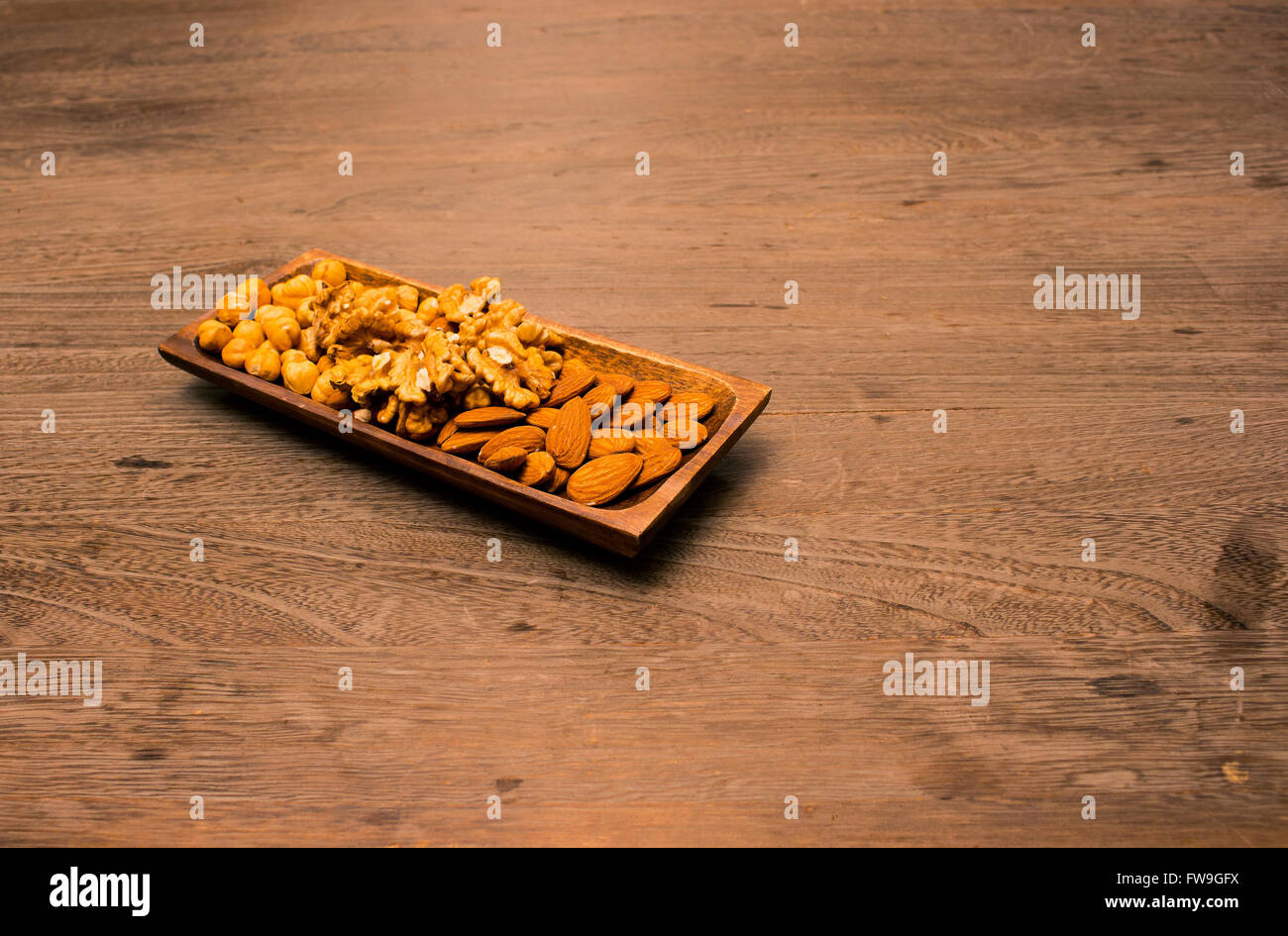 Rohe Mandeln und Nussbaum in Holz Platte auf Holztisch Stockfoto