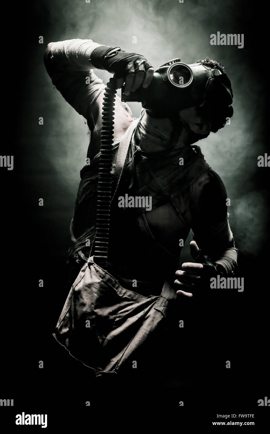 bandagierte Männer in die Gasmaske auf dem schwarzen Hintergrund, umgeben von Rauch und schaut zum Himmel empor, überleben Soldat nach apocalyp Stockfoto