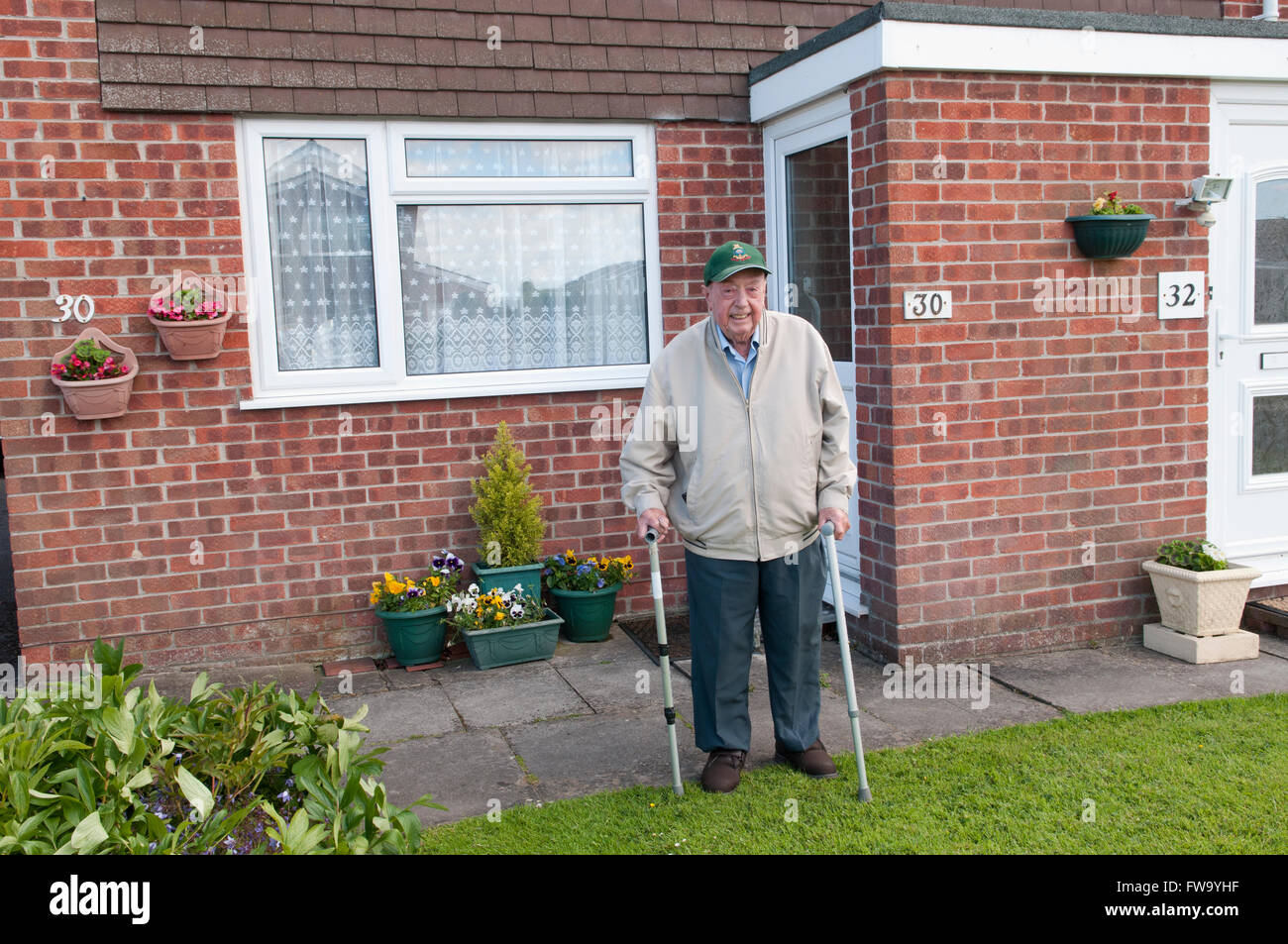 Porträt eines älteren Mannes mit zwei Stöcken in seinem Garten lächelnd Stockfoto