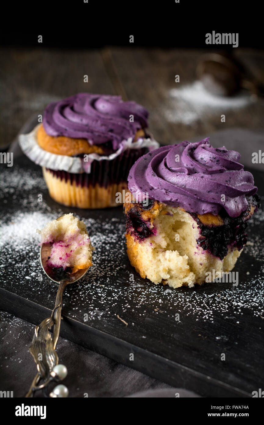 Blueberry Cupcakes mit lila Buttercreme auf schwarzer Holzplatte. Essen Stilleben, rustikalen Stil Stockfoto