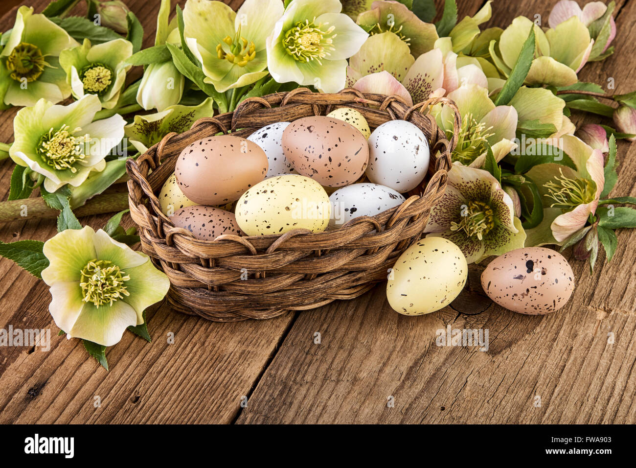 Korb mit Ostereier in Pastellfarben auf Holztisch Stockfoto