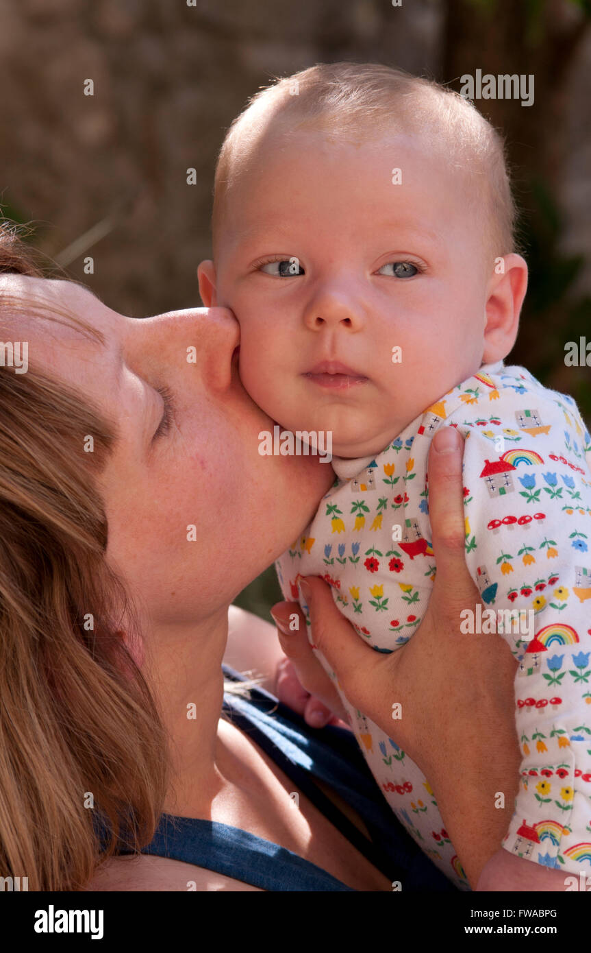 Baby wird von Mutter geküsst Stockfoto