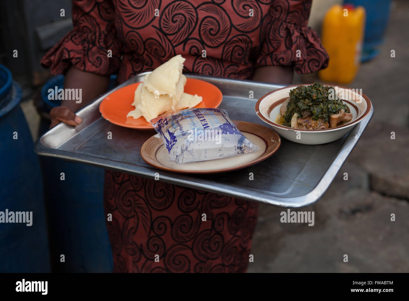Ein Tablett mit Essen, einschließlich einen Beutel des behandelten Wassers durchgeführt in einem Restaurant, Nigeria Afrika Stockfoto