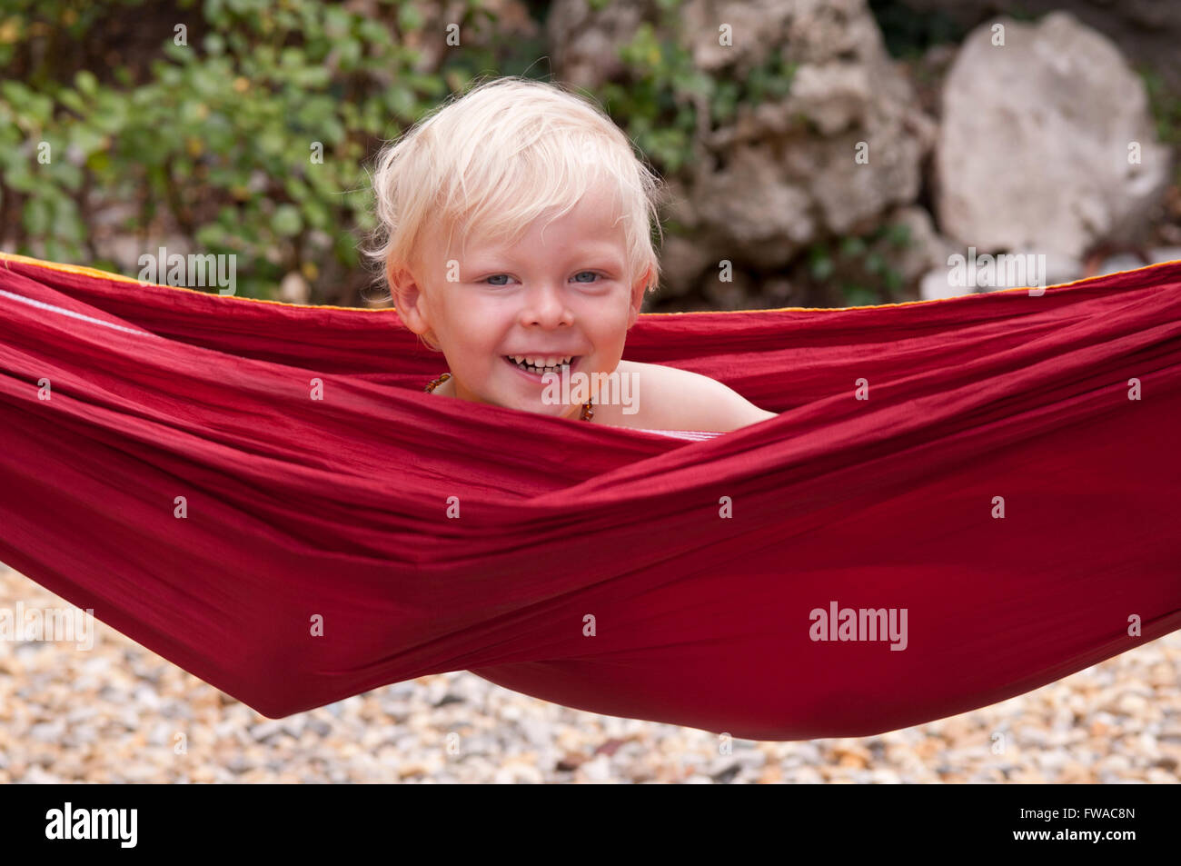 Nahaufnahme Portrait eines glücklich lächelnden jungen in einer roten Hängematte Stockfoto