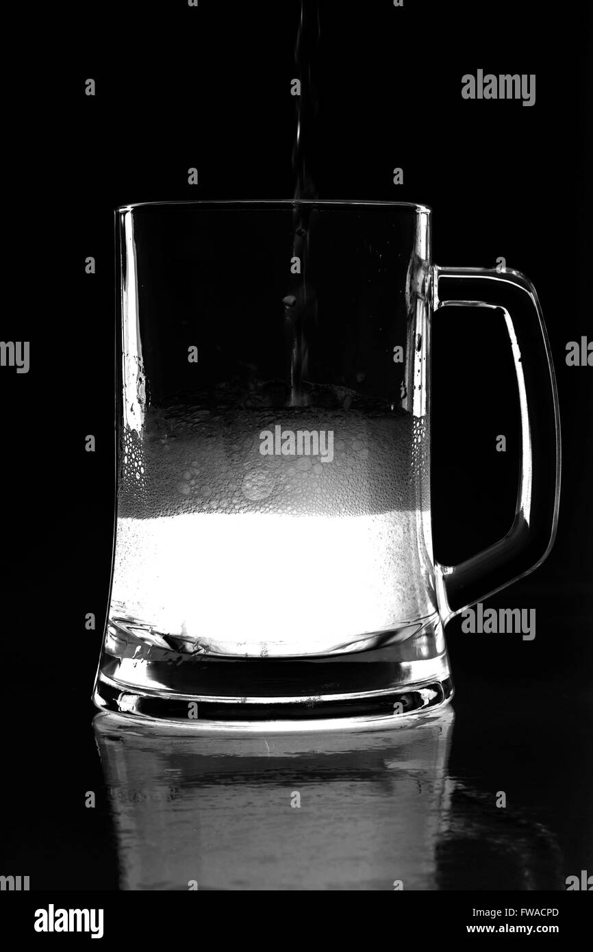 Foto von Bier mit Spiegelung im Glas mit Schaum und Bläschen auf weißem Hintergrund Stockfoto