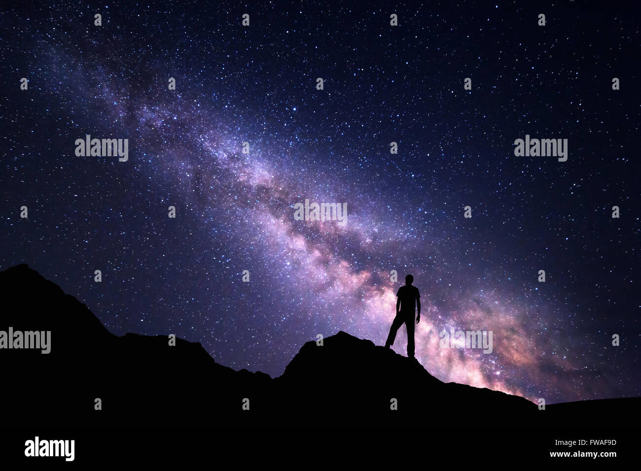 Landschaft mit Milky Way. Nachthimmel mit Sternen und Silhouette ein glücklicher Mann auf dem Felsen. Schöne Universum. Weltraum Hintergrund Stockfoto
