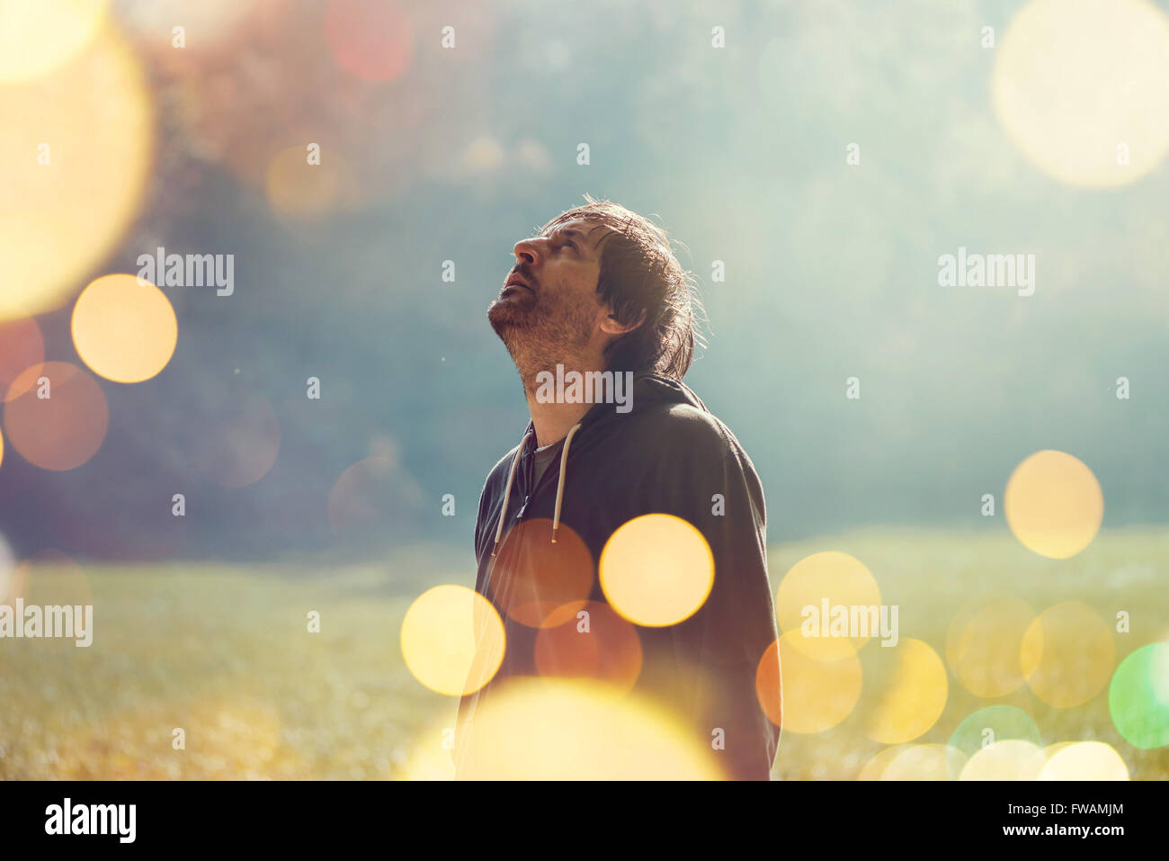 Erwachsenen Mannes ruht nach dem Joggen im Park stehen und blickte zum Himmel, getönten Retro Bild mit Tiefenschärfe und Bokeh Stockfoto
