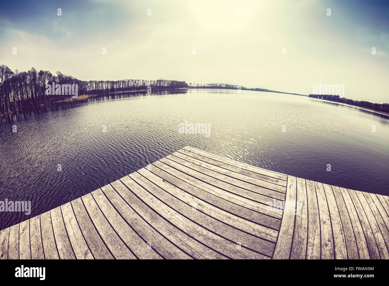 Alte Film Retro getönten fisheye-Objektiv Bild von einem Holzsteg am See bei Sonnenuntergang. Stockfoto