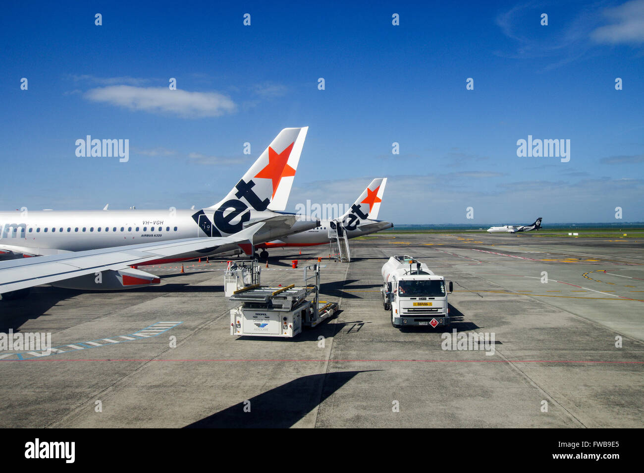 Tails von Jetstar Flugzeug geparkt auf dem Vorfeld in Auckland Flughafen mit Air New Zealand Rollen im Hintergrund Stockfoto