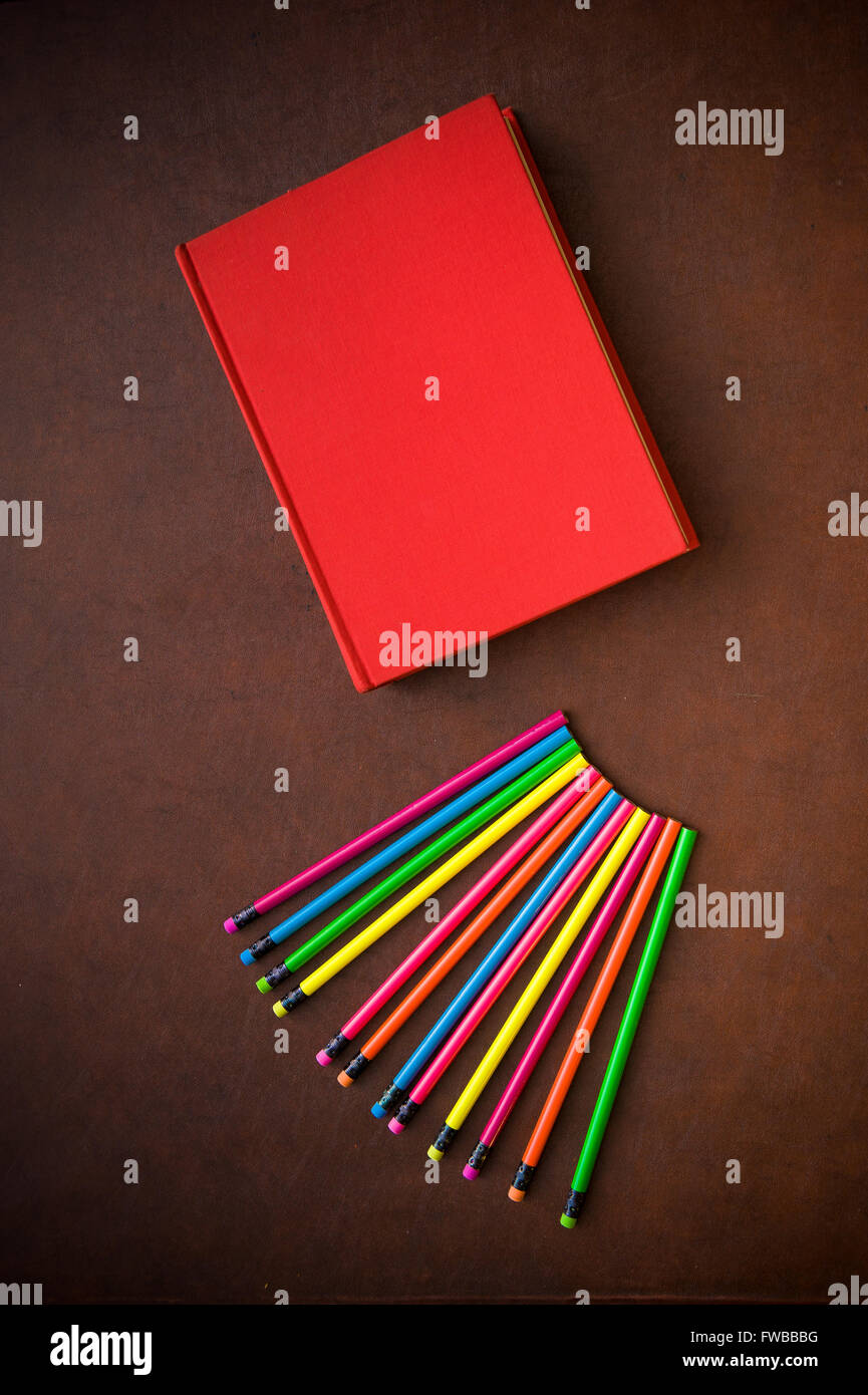 Hölzerne Schriftsteller Desktop mit bunten Bleistift und rote leere Cover Buch, vertikalen Rahmen Stockfoto