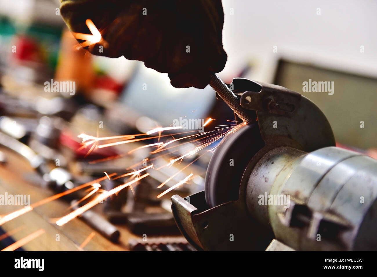 Mechaniker Polieren eine Schraube am industriellen Poliermaschine in einer Garage. Sparks entstammen Schleifscheibe. Stockfoto