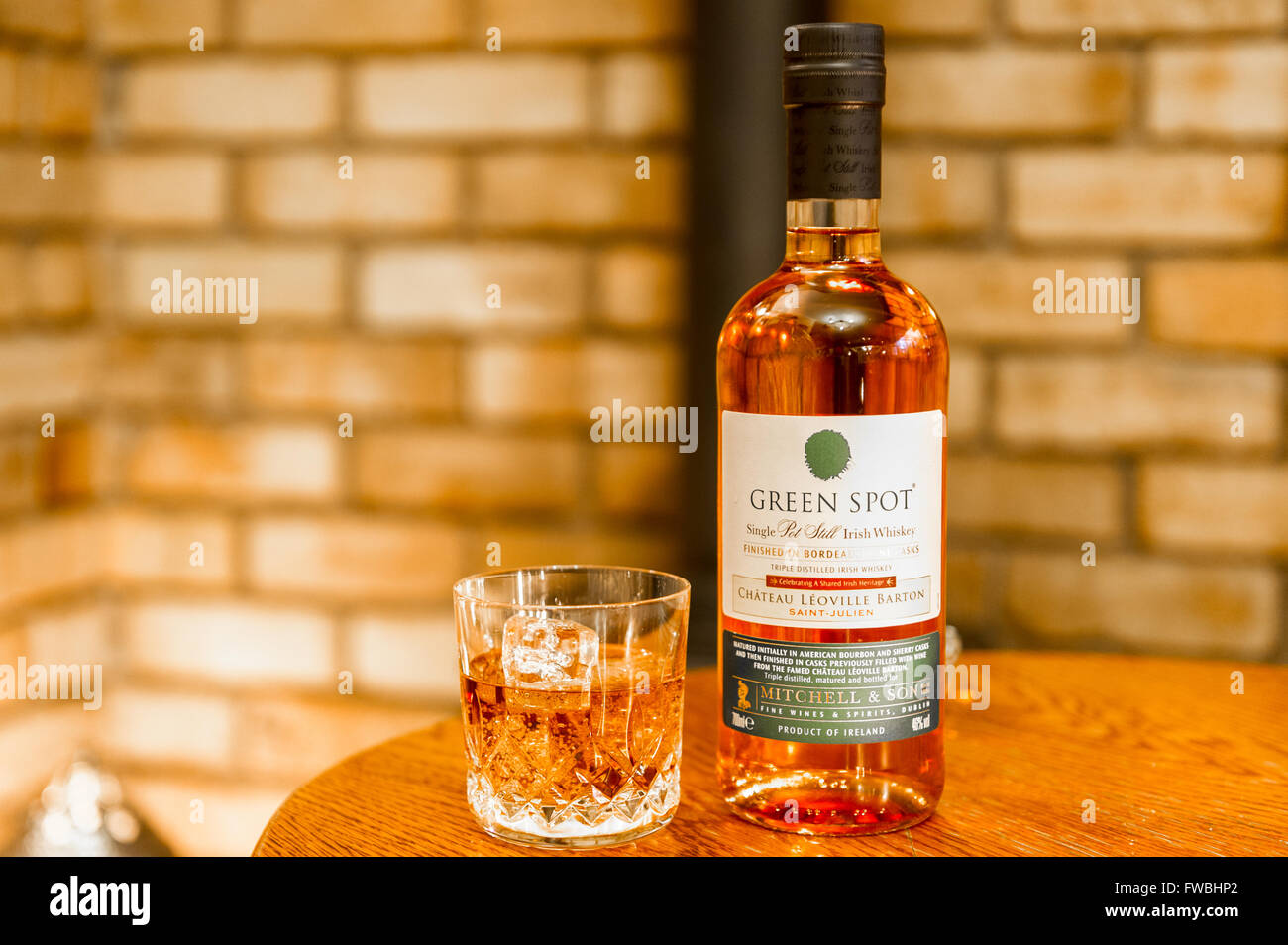 Flasche dreifach destillierter Green Spot Whiskey mit einem Glas Whiskey mit Eiswürfeln. Stockfoto