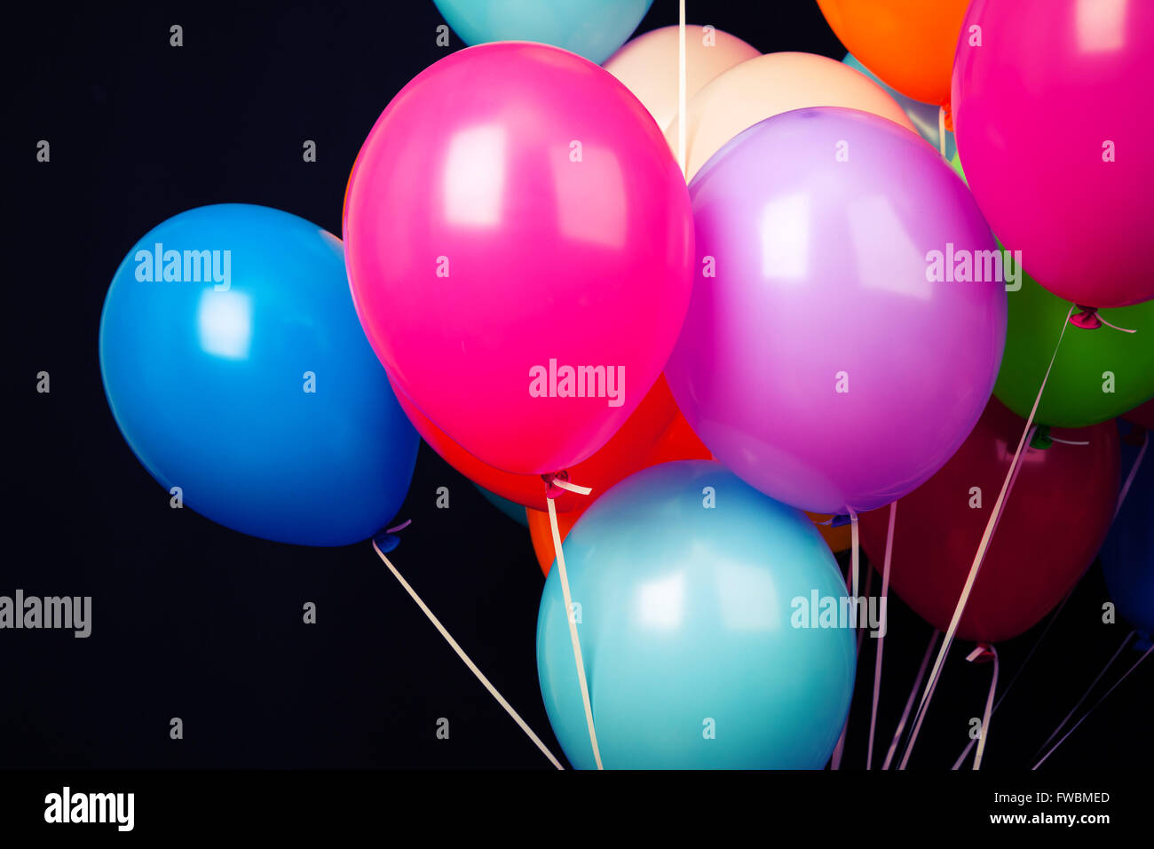 Gruppe von bunten Luftballons auf Bändern auf schwarzem Hintergrund Stockfoto