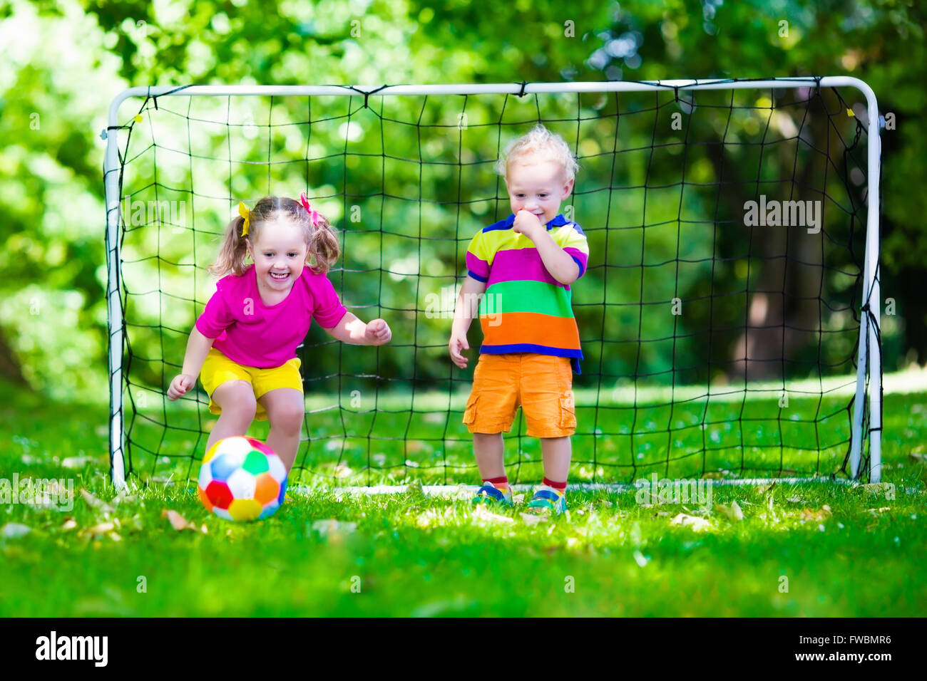Zwei glückliche Kinder spielen Fußball im Freien im Schulhof. Kinder spielen Fußball. Aktiv Sport für Vorschulkind. Stockfoto