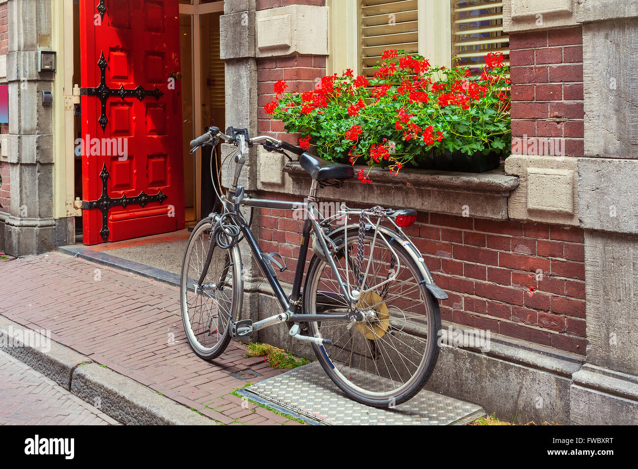 Fahrrad gelehnt Ziegelmauer und Fensterbank mit Blumen Topf in Amsterdam, Niederlande. Stockfoto