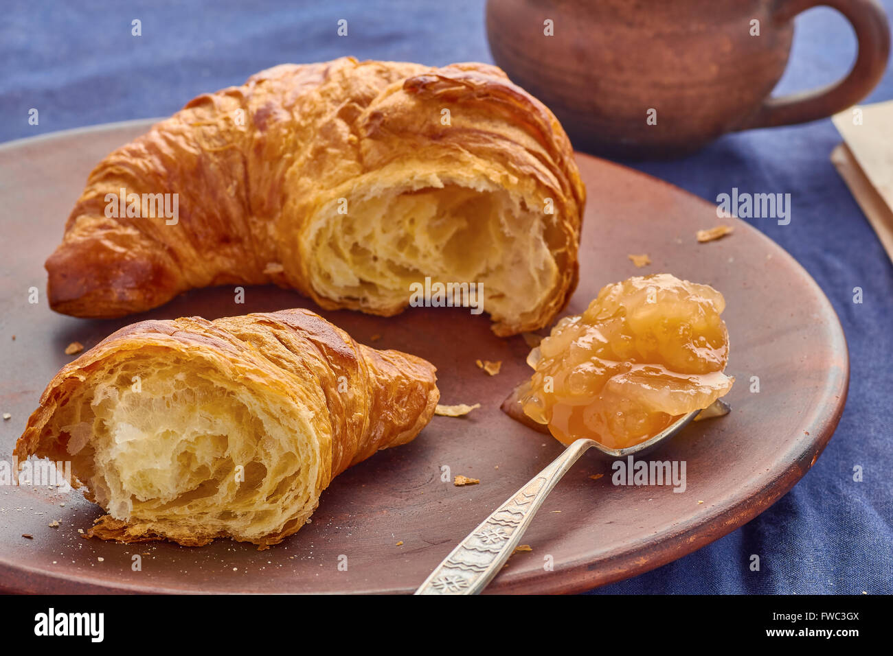 Gebrochene Croissant, Löffel Apfel Marmelade und eine Tasse Stockfoto