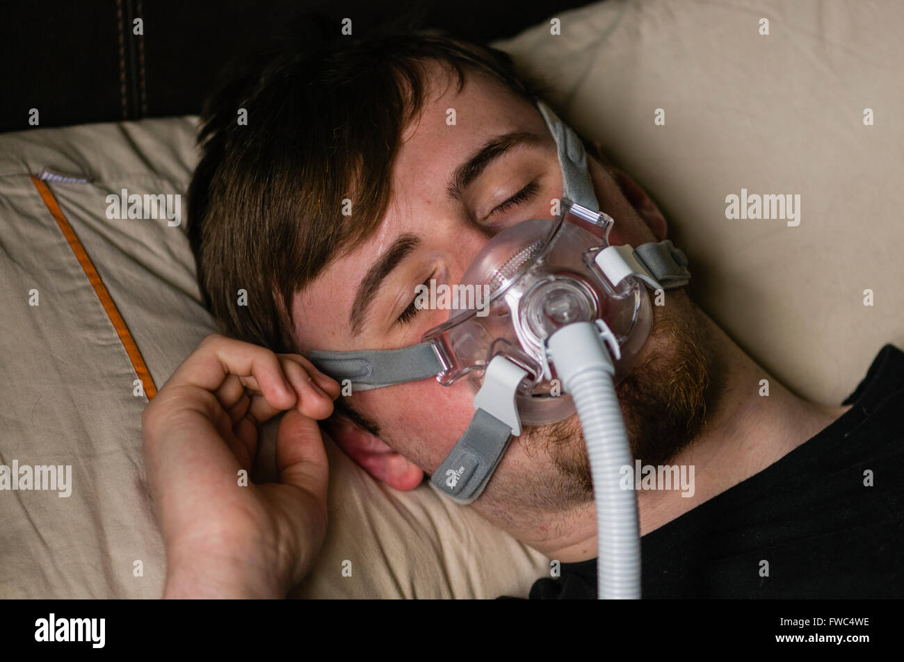 Ein Mann im Bett in der Nacht mit einem Philips Respironics System ein CPAP-Gerät mit Amara Ansicht Maske Stockfoto