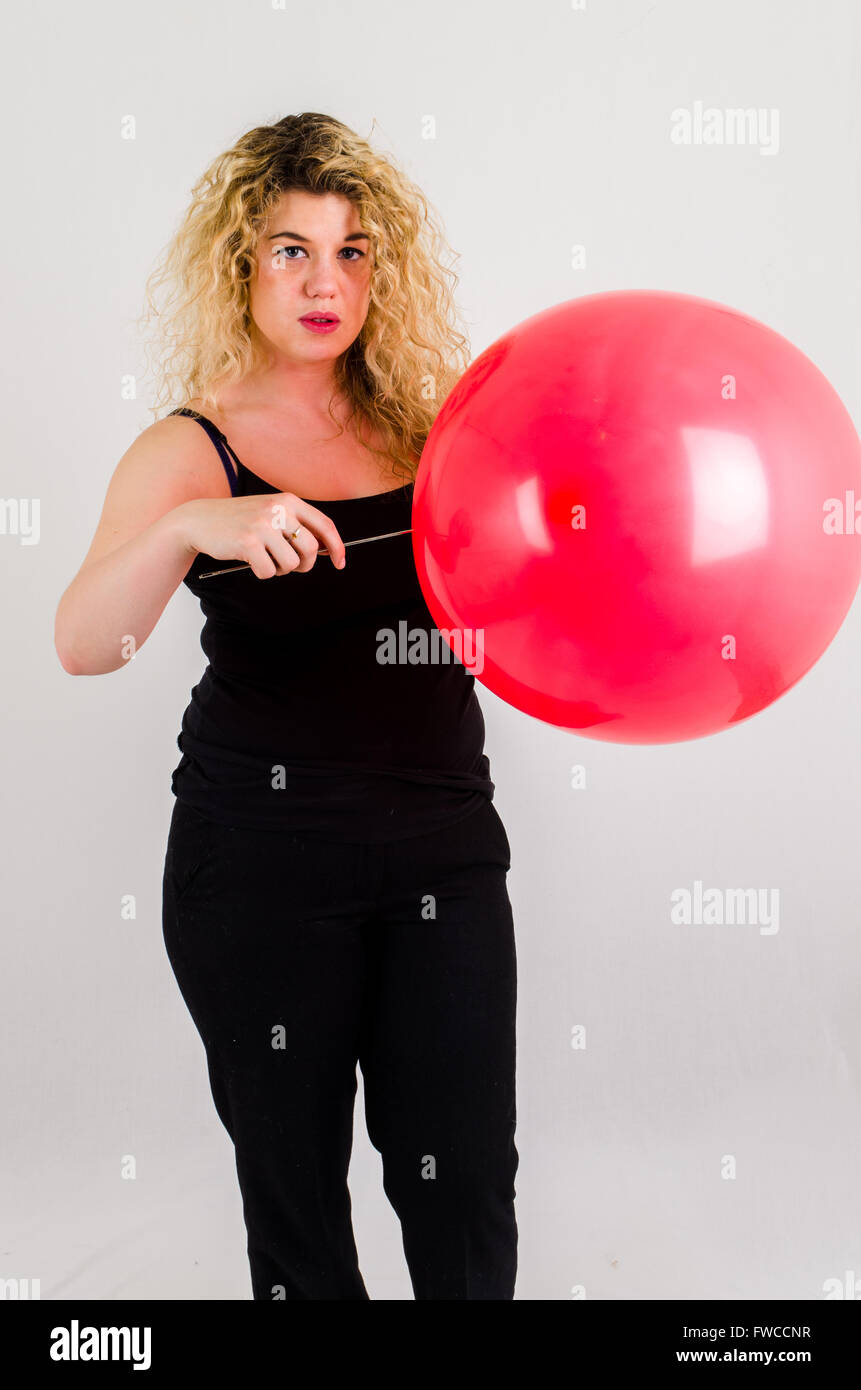 Einzelne Erwachsenfrau Sprengung ein Medium sized roten Ballon Stockfoto