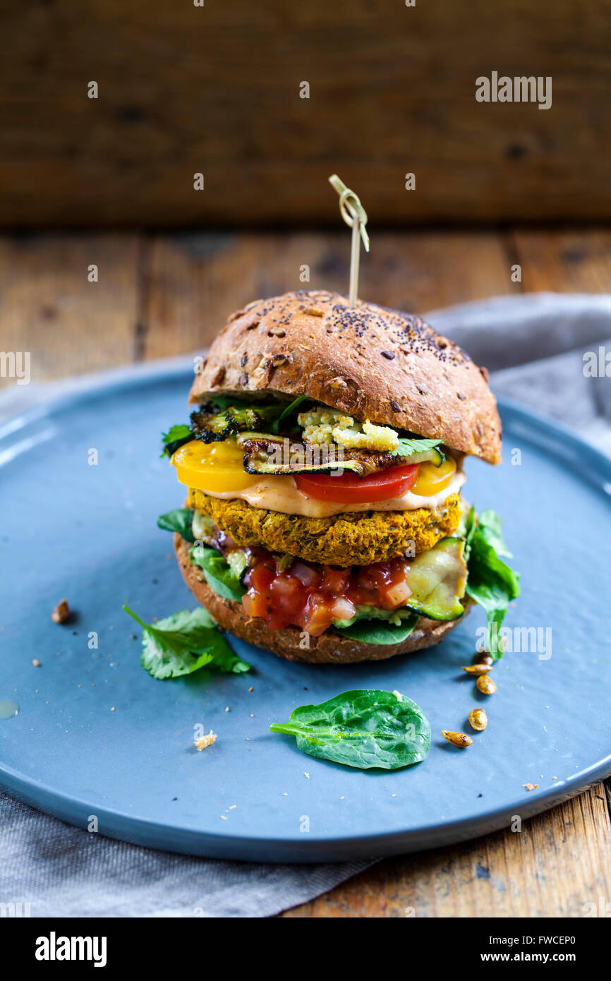 Butternut-Kürbis und Kichererbsen-Burger mit Tomaten-Salsa, Spinat, Avocado und gebratenen Zucchini Stockfoto