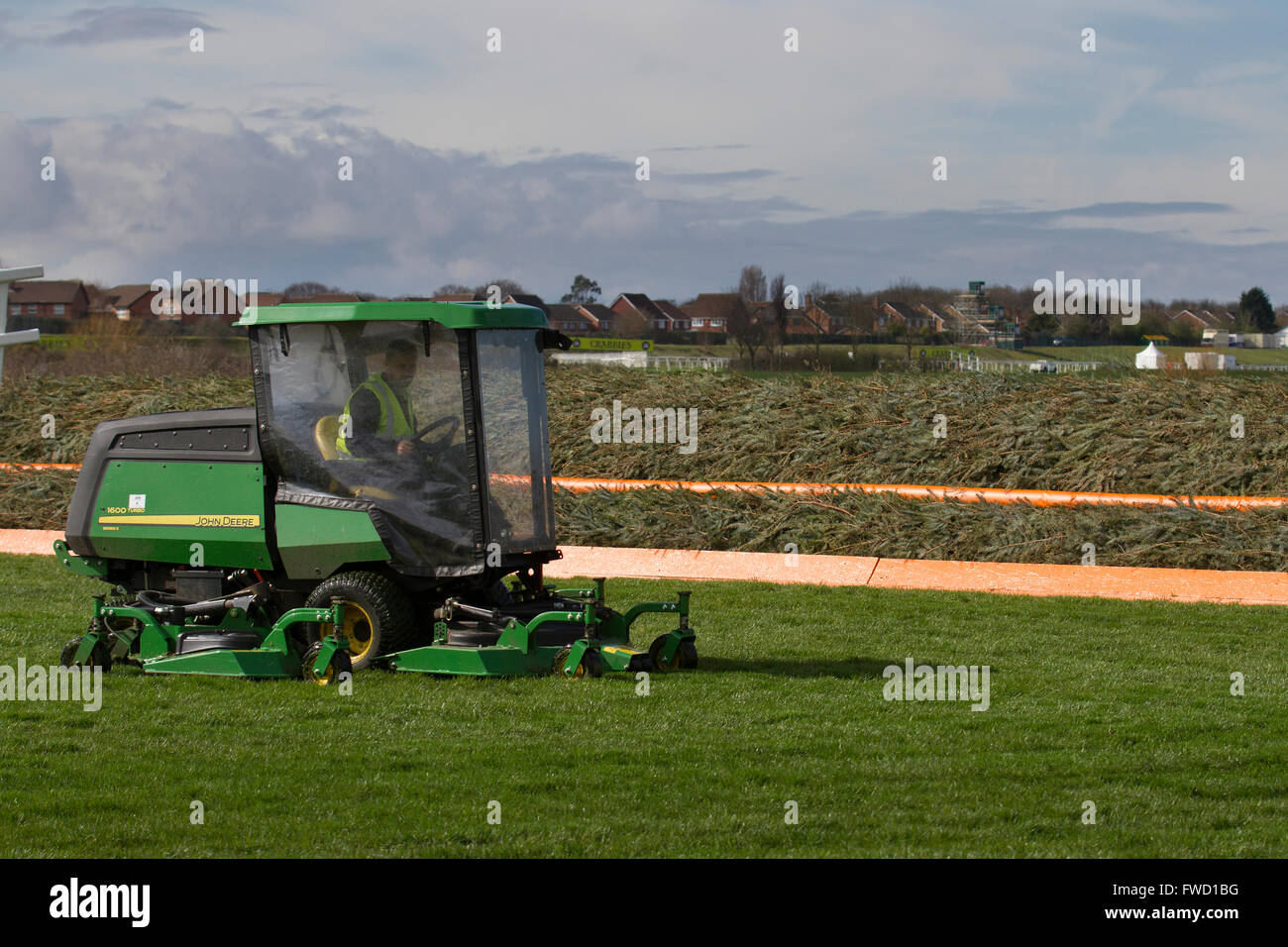 Pferderennbahn Wartung Liverpool, Merseyside, UK laufenden Vorbereitungen für die Aintree Grand National. Auftragnehmer, mit einem John Deere 1600 Turbo Serie II, sind auf der Website zu beenden, das Pferd-Racing Event, der am Donnerstag beginnt ihren Höhepunkt in Was ist der weltweit größte Pferd Rennen am Samstag Nachmittag beschäftigt. Stockfoto