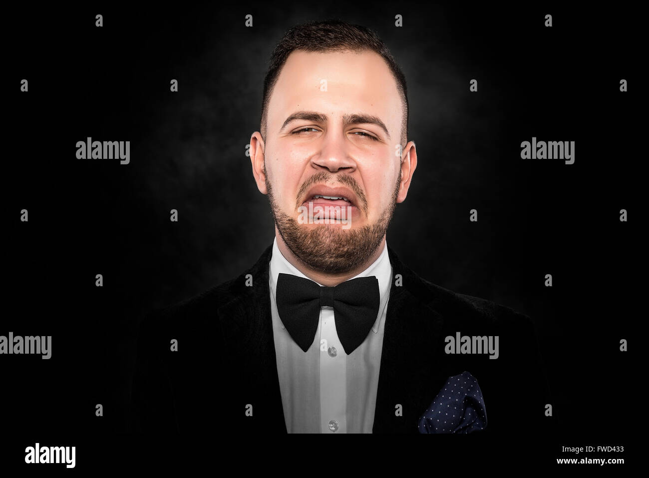 Deprimiert hübscher junger Mann im Anzug auf dunklem Hintergrund. Stockfoto