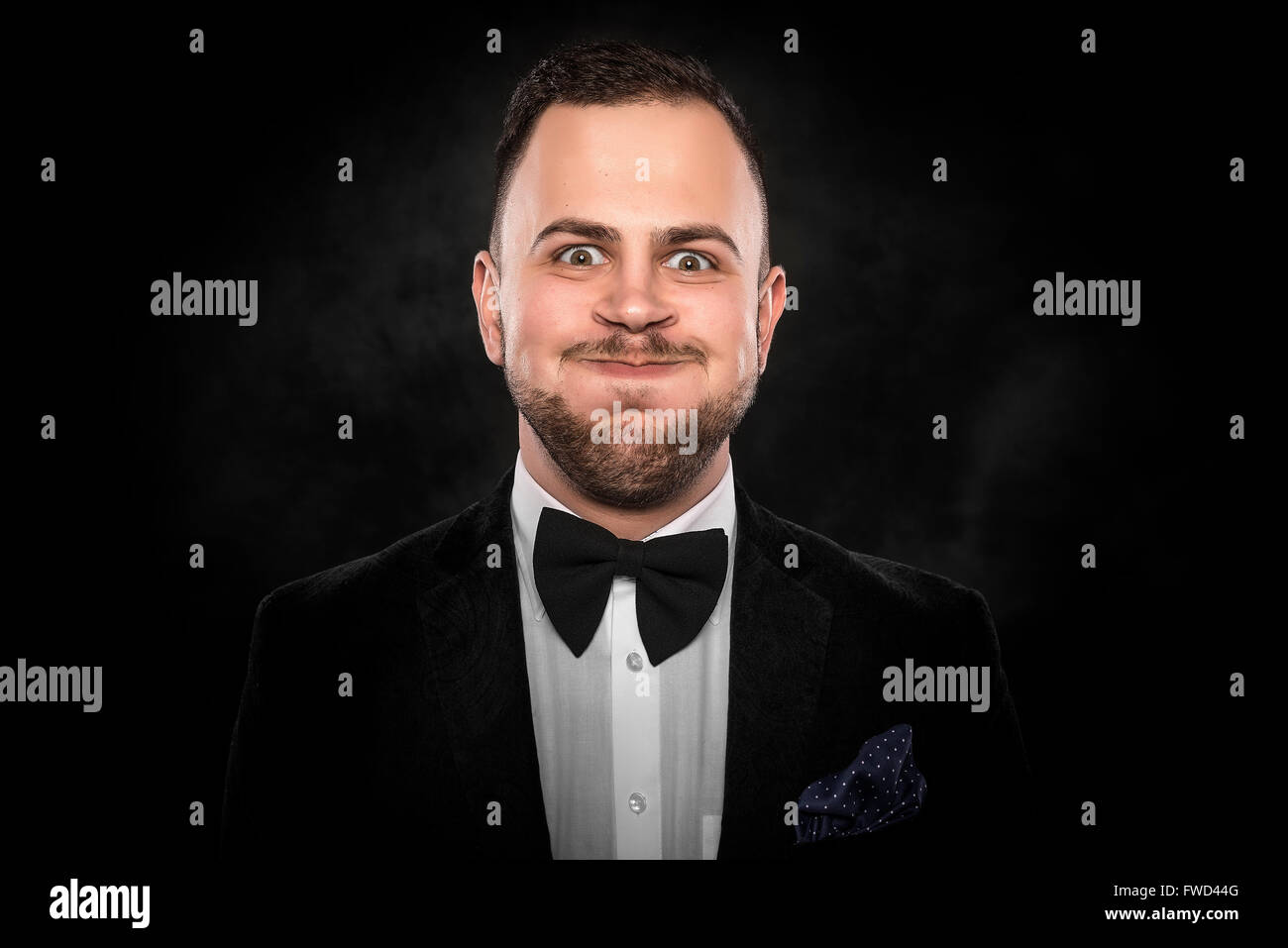 Mann im Anzug macht lustige Gesicht auf dunklem Hintergrund Stockfoto
