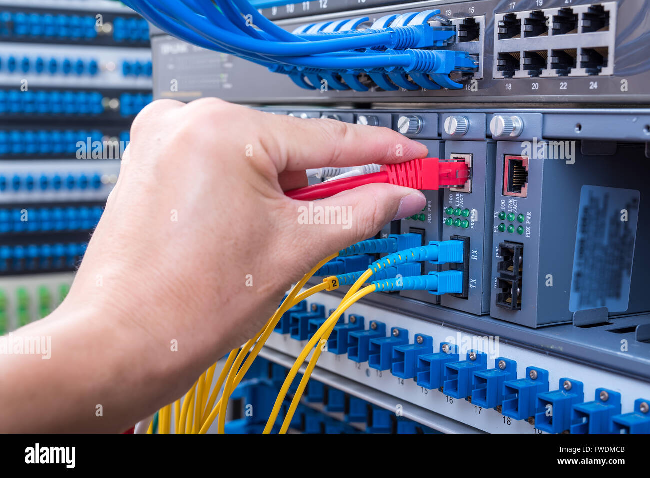 Mann bei der Arbeit im Netzwerk Server Zimmer mit LWL-Hub für die digitale Kommunikation und Internet Stockfoto