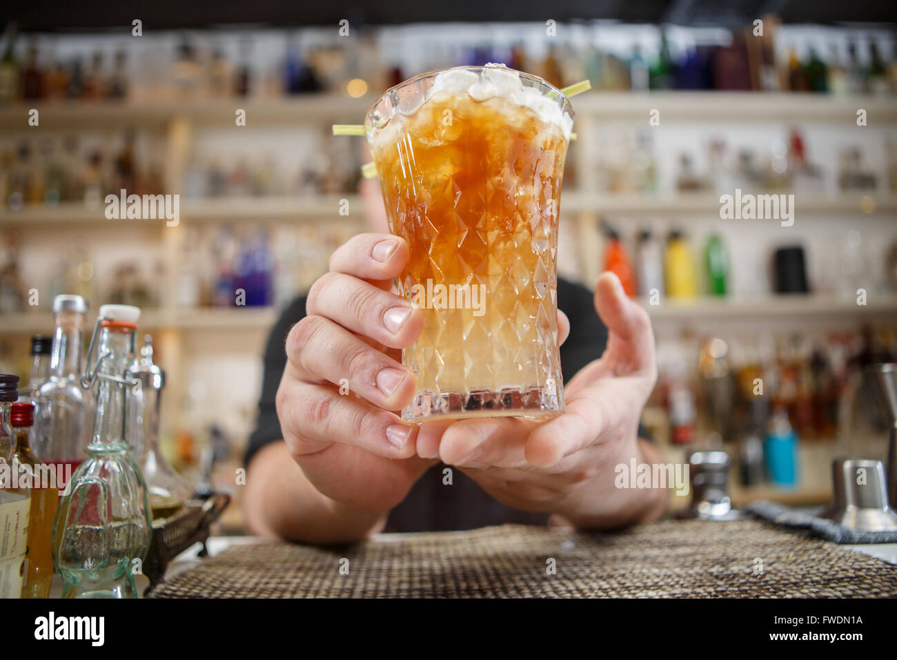 Barkeeper steht in Pubб mit cocktail und geben Glas nach vorne. Getränke im Mittelpunkt. Stockfoto