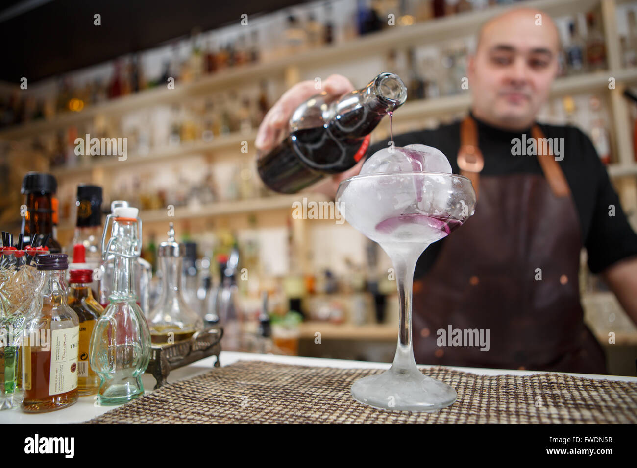 Barkeeper gießt Wein im Glas mit Rieseneishöhle, Weitwinkel-Bild. Stockfoto