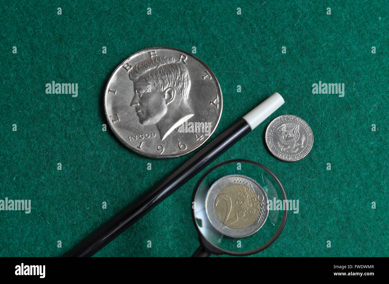Zauberstab mit europäischen und amerikanischen Münzen auf einer grünen Casino-Matte Stockfoto