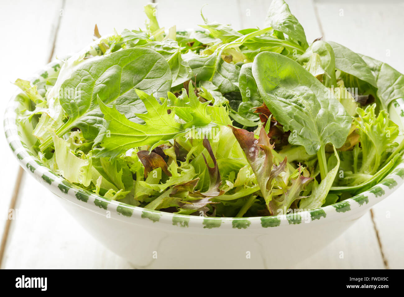 gemischte Salatblätter in eine Schüssel geben Stockfoto