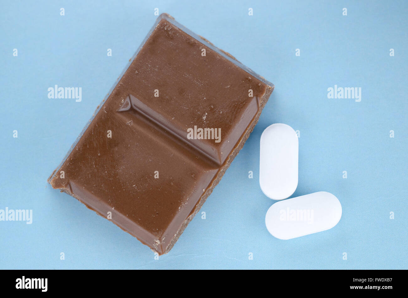Schokolade-Trigger Migräne Kopfschmerzen Konzept mit Stück Schokolade und zwei Schmerzmittel Tabletten Stockfoto