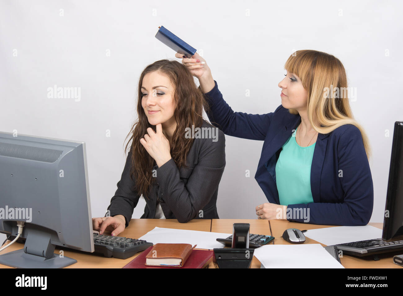 Büroangestellte, die heimlich gehen, mit einem Kollegen-Notebook auf den Kopf schlagen Stockfoto