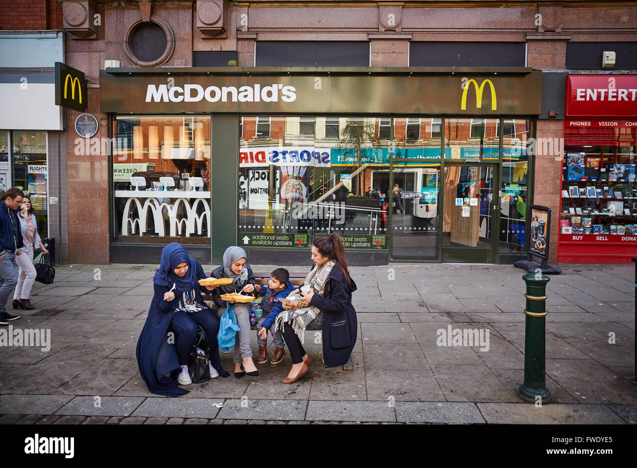 Oldham Stadtzentrum Yorkshire Street McDonalds Fastfood Imbiss Burger grün design außen asiatische Damen als draußen zu sitzen Stockfoto