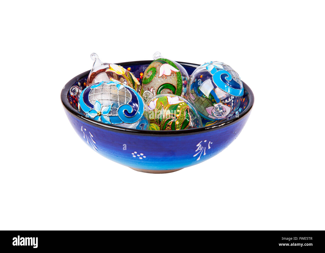 Bunte Zusammensetzung von fünf ornamentalen Eiern aus Glas, die in einer tiefen Blau gemusterten Keramik Kappe sind.  Isoliert auf weiss. Stockfoto