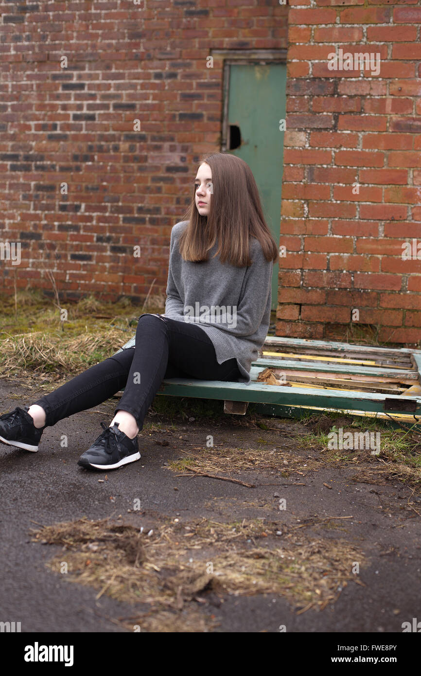 Hübsche junge Teenager-Mädchen sitzen auf einige alten Türen außerhalb eines verlassenen Gebäudes Stockfoto