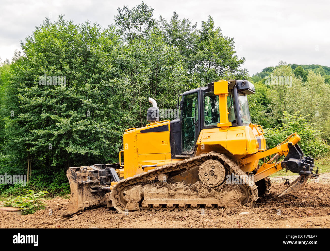 Gelb und schwarz kleine Planierraupe mit Schlamm bedeckt. Stockfoto