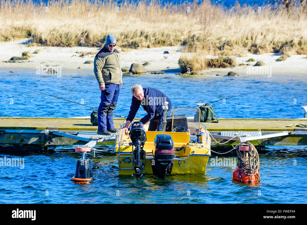 Kivik, Schweden - 1. April 2016: Zwei Männer immer bereit, eine gelbe Motorboot für Angeln herausnehmen. Eine Person Stand auf dem pi Stockfoto