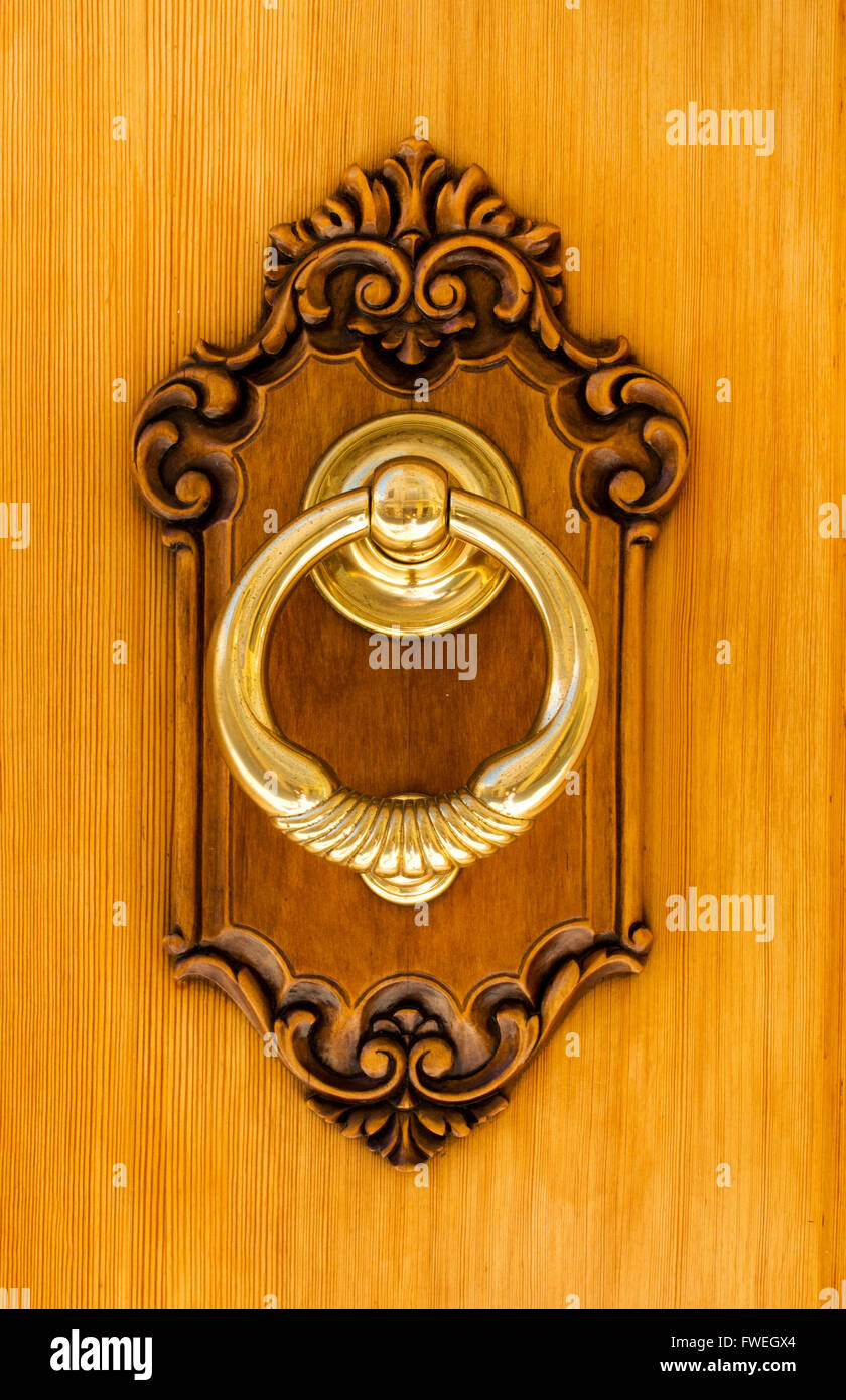 Authentische moderne spanische Messing-Türklopfer. zeigt schwere Messing Klopfer inmitten einer geschnitzten Kiefer auf einer Haustür Stockfoto