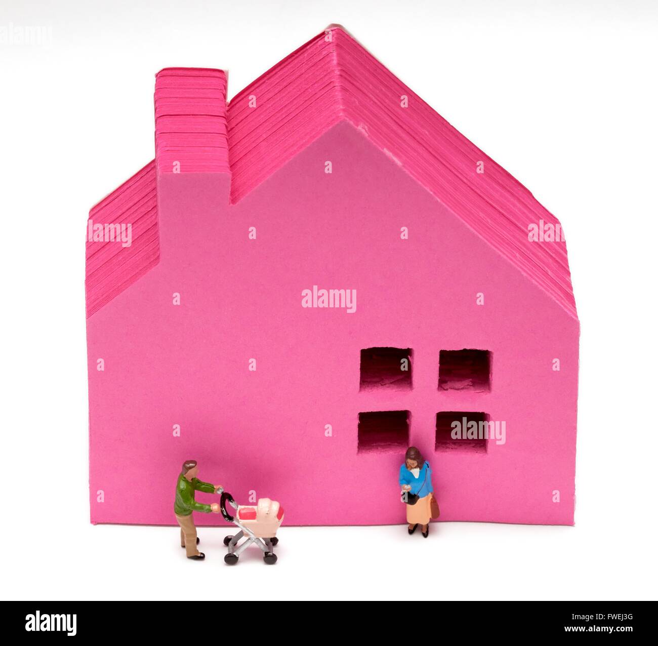 Ein Miniatur-paar vor einem rosa Haus erste Zeit Buyer-Konzept. Stockfoto