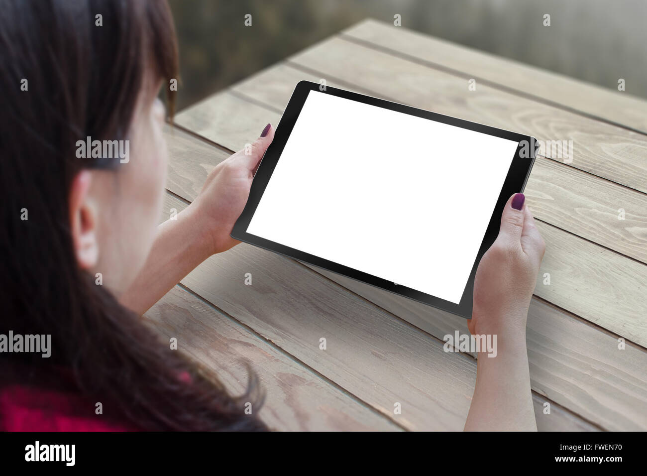 Schwarz Tablet mit leeren, weißen, isolierte Bildschirm für Mock-up in der Hand der Frau. Tabelle im Hintergrund. Stockfoto