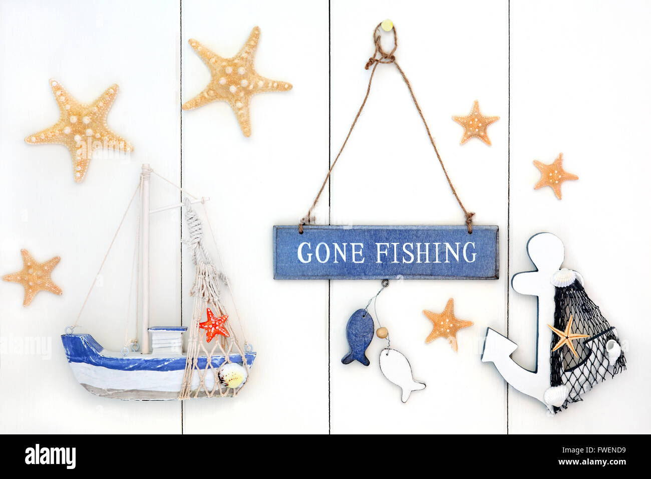 Zusammenfassung Hintergrund mit gone Fishing Zeichen, Seestern, dekorative Anker und Boot über weißem Holz. Stockfoto